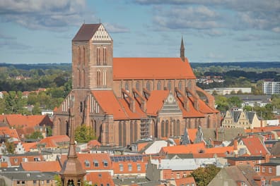 Blick auf die Kirche St. Nikolai in Wismar, umgeben von Altstadthäusern mit roten Dächern