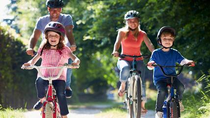 Ein Mann, eine Frau und zwei Kinder auf Fahrrädern bei Sonnenschein.