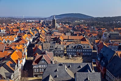 Blick über die meist roten, teils schwarzen Dächer der Altstadt von Goslar, aus denen sich ein Kirchturm erhebt